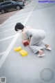 A woman in a gray dress crouching down in a parking lot.