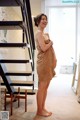 A woman in a towel standing in front of a staircase.