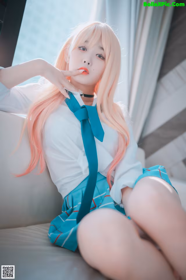 A woman with long pink hair sitting on a couch.