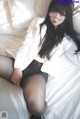 A woman in a white shirt and black pantyhose laying on a bed.