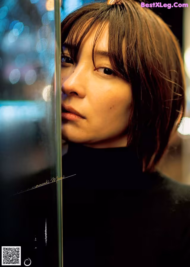 A woman with short hair looking out of a window.