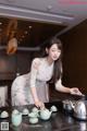 A woman in a kitchen preparing tea on a stove.