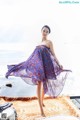 A woman in a purple dress standing on a beach.