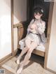 A woman in a white dress is sitting on a bed.