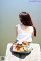 A woman sitting on a ledge looking out over the water.