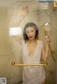 A woman in a white dress standing in a shower.