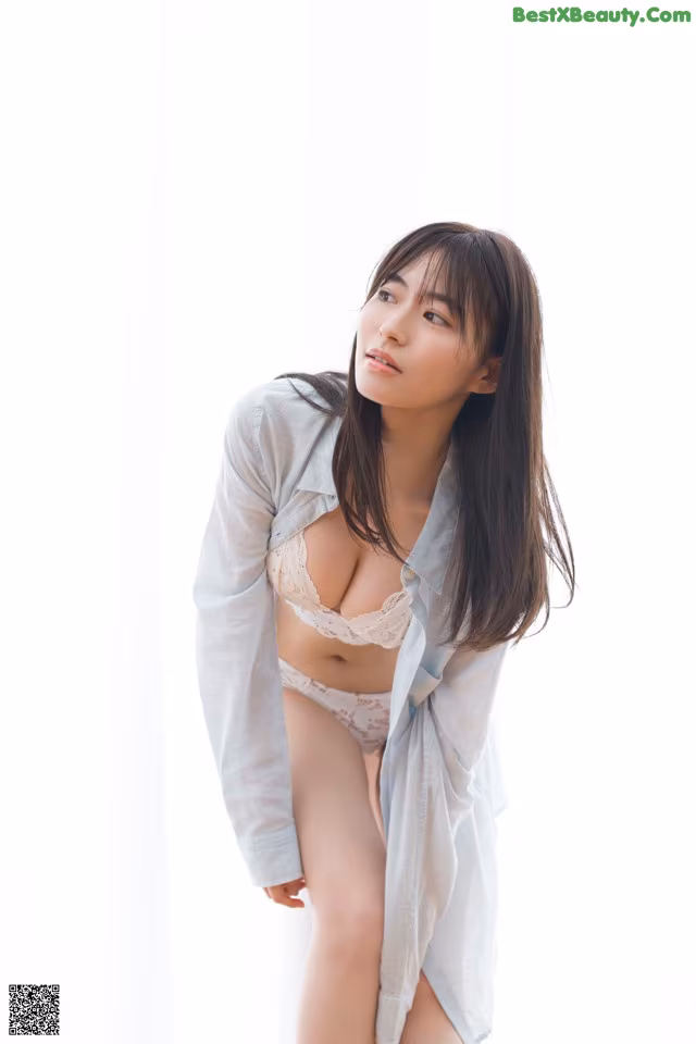 A woman in a white shirt and panties posing for a picture.