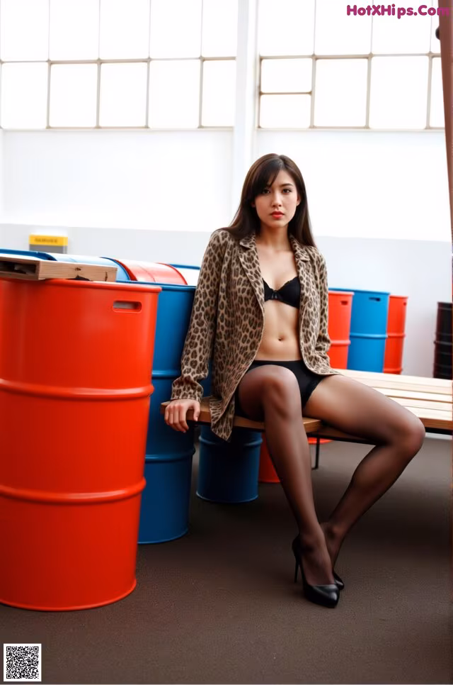 A woman sitting on top of a wooden bench next to red barrels.