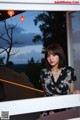 A woman standing in front of a window looking out at the sunset.