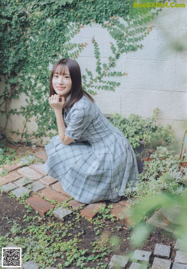 A woman sitting on the ground in front of a wall.