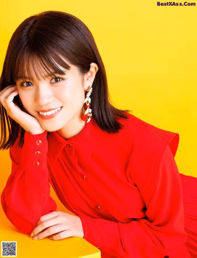 A woman in a red dress sitting on a yellow table.