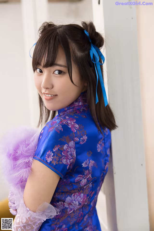 A woman in a blue and purple dress posing for a picture.