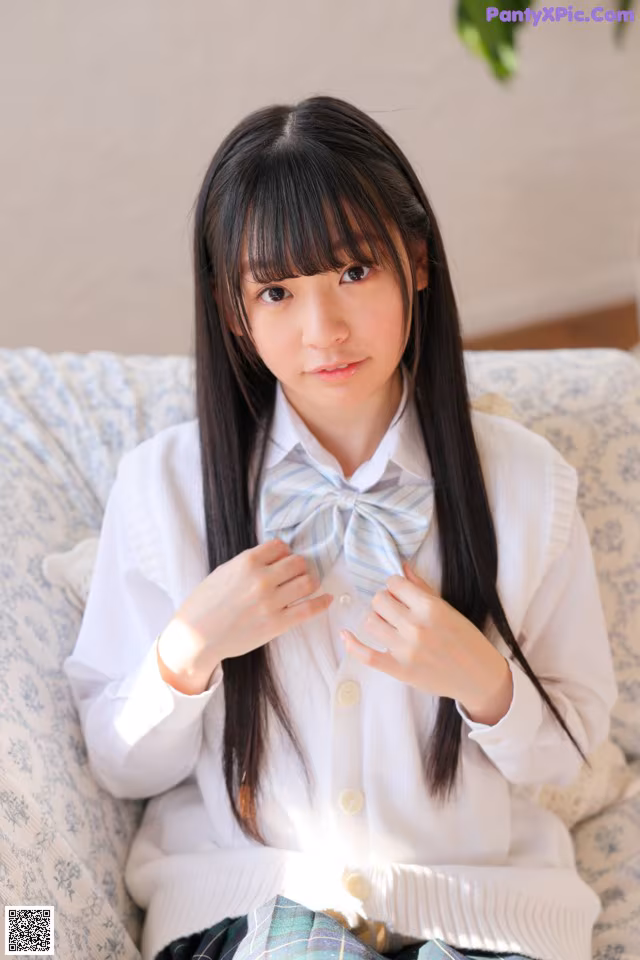 A young woman sitting on a couch with a bow tie.